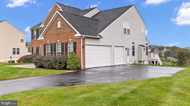 view of front of home with driveway, a garage, brick siding, central air condition unit, and a front yard