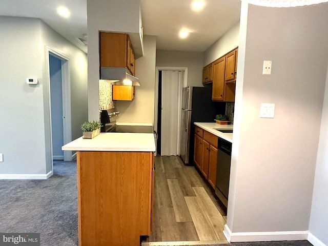 kitchen with brown cabinetry, appliances with stainless steel finishes, light countertops, and backsplash