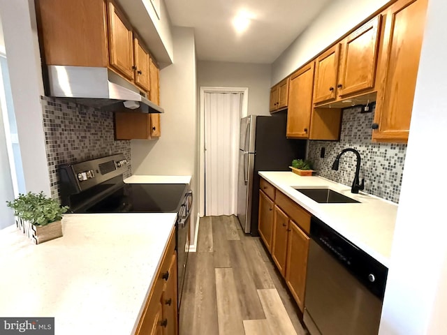 kitchen with under cabinet range hood, a sink, light wood-style floors, light countertops, and appliances with stainless steel finishes