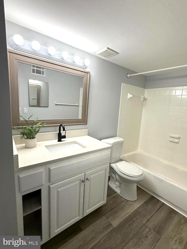 full bathroom featuring toilet, shower / bath combination, wood finished floors, vanity, and visible vents