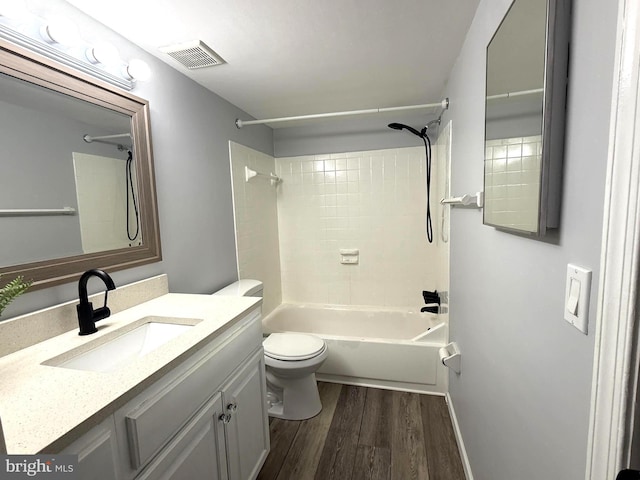 bathroom with visible vents, toilet, wood finished floors, vanity, and shower / washtub combination