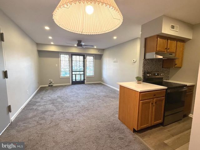 kitchen with under cabinet range hood, baseboards, backsplash, brown cabinets, and electric range oven