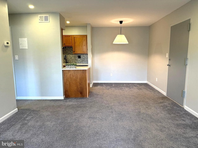 kitchen featuring visible vents, hanging light fixtures, decorative backsplash, brown cabinetry, and dark carpet