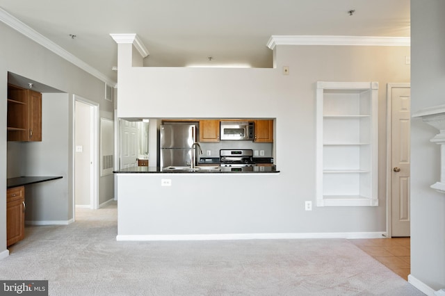 kitchen featuring dark countertops, crown molding, light colored carpet, brown cabinets, and appliances with stainless steel finishes