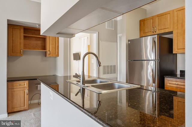 kitchen featuring dark stone countertops, visible vents, open shelves, freestanding refrigerator, and a sink