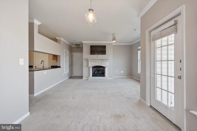 unfurnished living room featuring a fireplace with raised hearth, baseboards, carpet, and ornamental molding