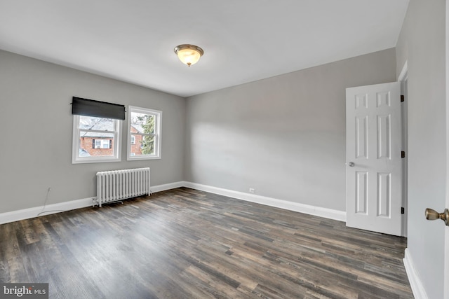 spare room with baseboards, radiator heating unit, and wood finished floors