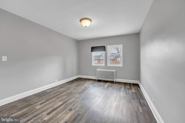 empty room with baseboards, dark wood-type flooring, and radiator