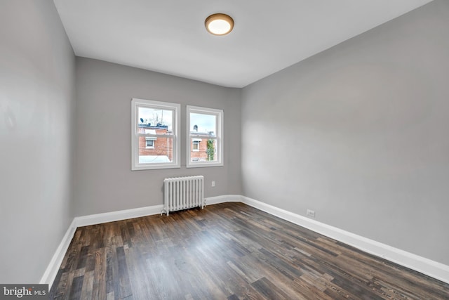 empty room with radiator, baseboards, and dark wood finished floors