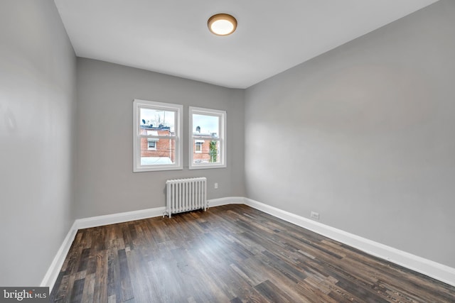 empty room with dark wood-style floors, radiator heating unit, and baseboards