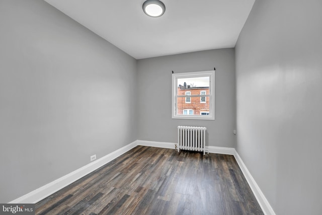 empty room with radiator, baseboards, and dark wood-type flooring