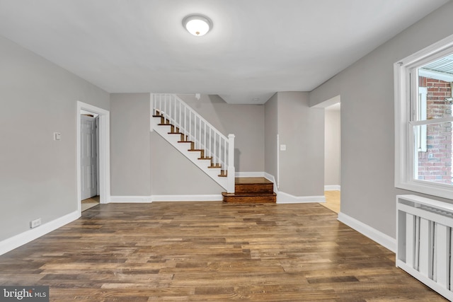 interior space with stairs, radiator heating unit, baseboards, and wood finished floors