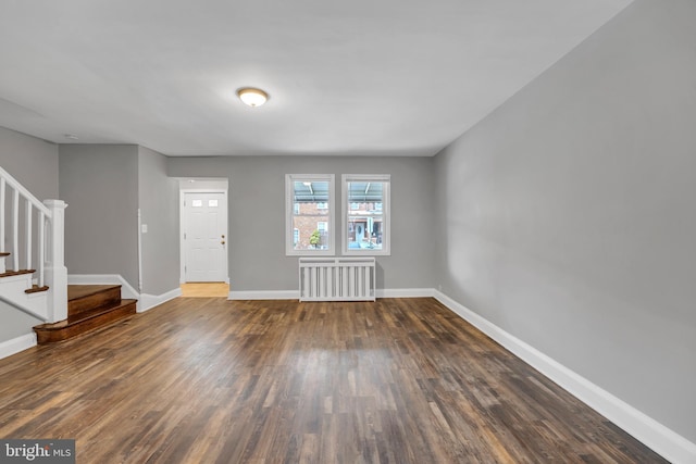 foyer entrance with stairway, radiator heating unit, wood finished floors, and baseboards