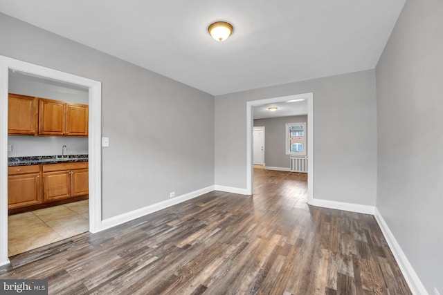 unfurnished dining area featuring a sink, baseboards, and wood finished floors