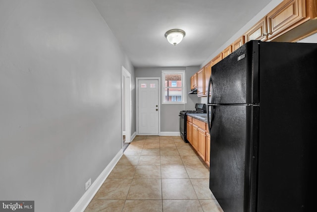 kitchen featuring light tile patterned floors, black appliances, under cabinet range hood, and baseboards