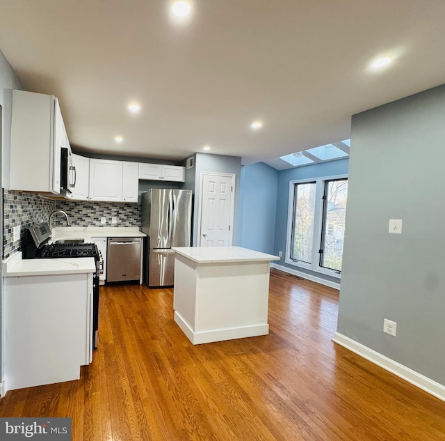 kitchen with dark wood-style flooring, stainless steel appliances, decorative backsplash, and a center island