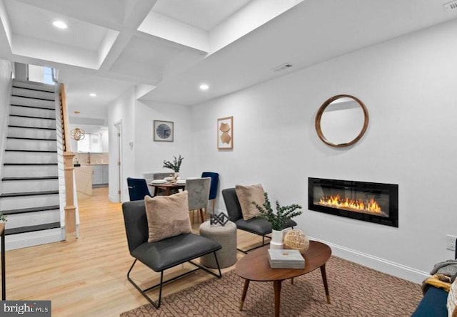 living area with light wood-style floors, recessed lighting, stairs, and a glass covered fireplace