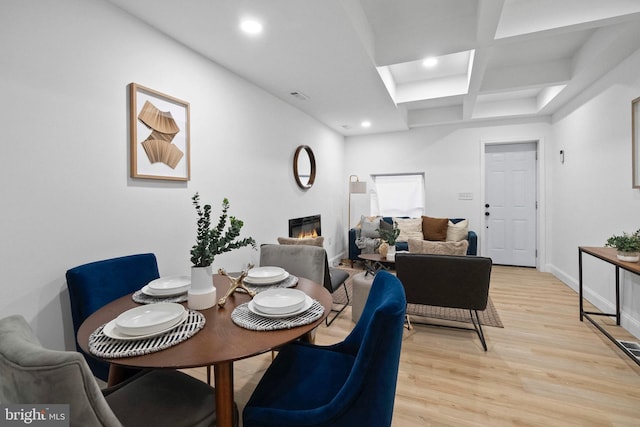 dining area with coffered ceiling, recessed lighting, light wood-type flooring, baseboards, and a glass covered fireplace