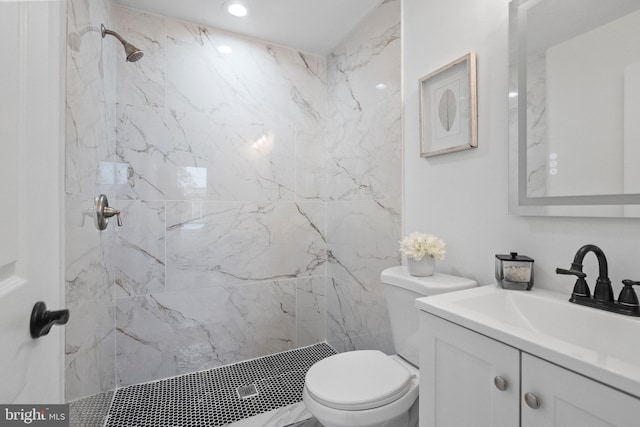bathroom featuring a marble finish shower, toilet, and vanity