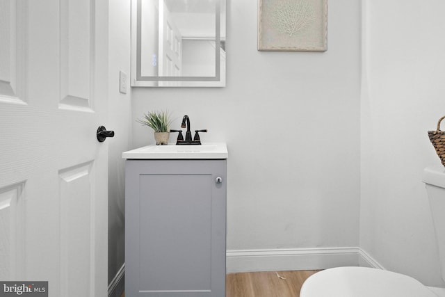 bathroom featuring toilet, vanity, baseboards, and wood finished floors