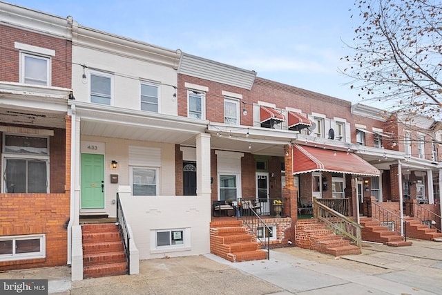 townhome / multi-family property featuring a porch and brick siding