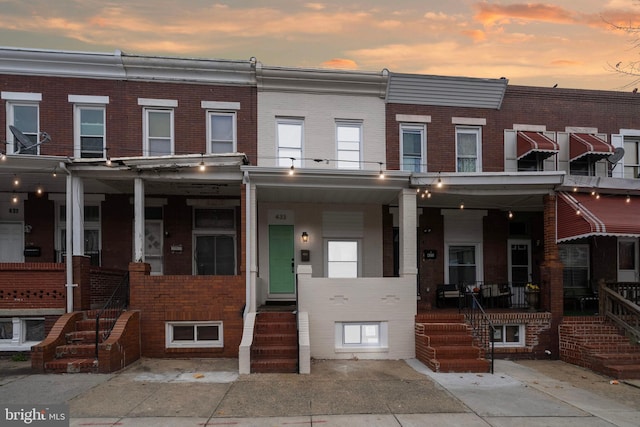 multi unit property with brick siding and a porch