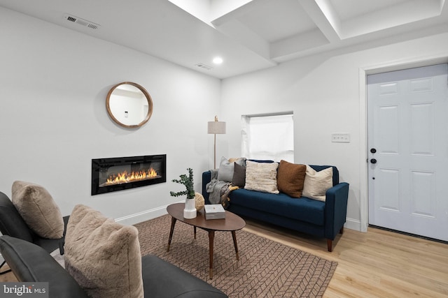 living room with light wood finished floors, baseboards, visible vents, and a glass covered fireplace