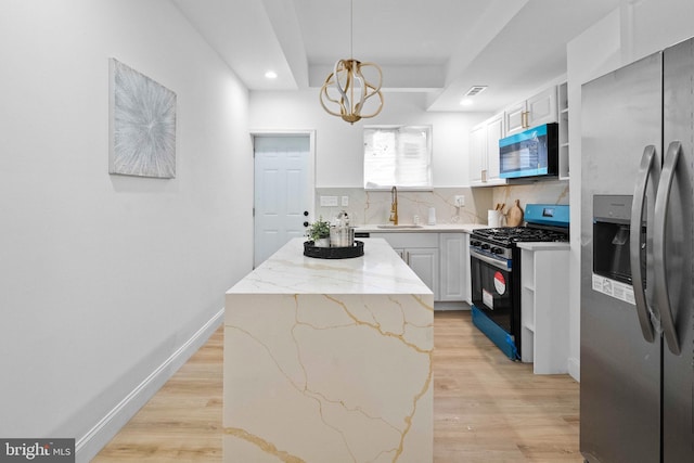 kitchen featuring stainless steel appliances, a sink, a kitchen island, light wood-style flooring, and light stone countertops