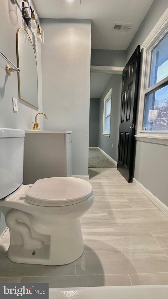 bathroom with toilet, baseboards, visible vents, and wood finished floors