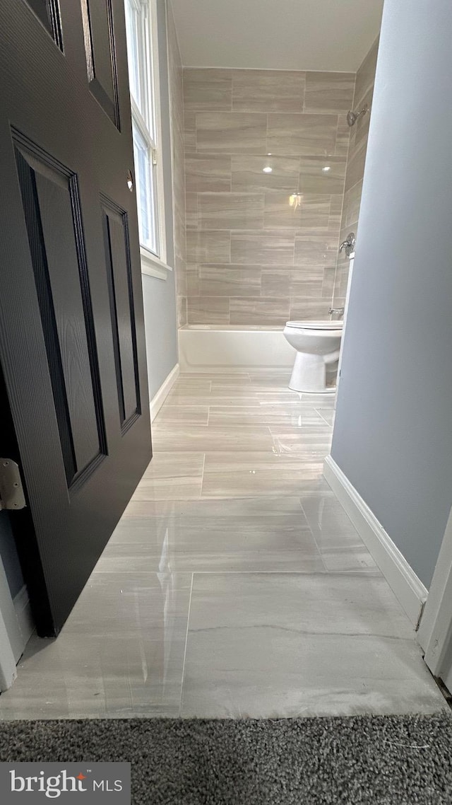 bathroom with toilet, baseboards, and bathing tub / shower combination