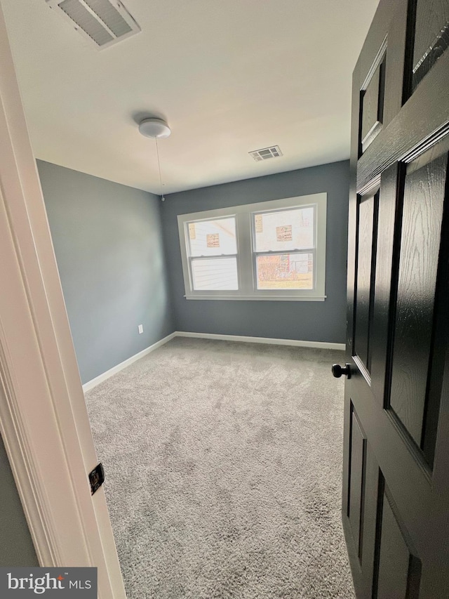 carpeted spare room with visible vents and baseboards