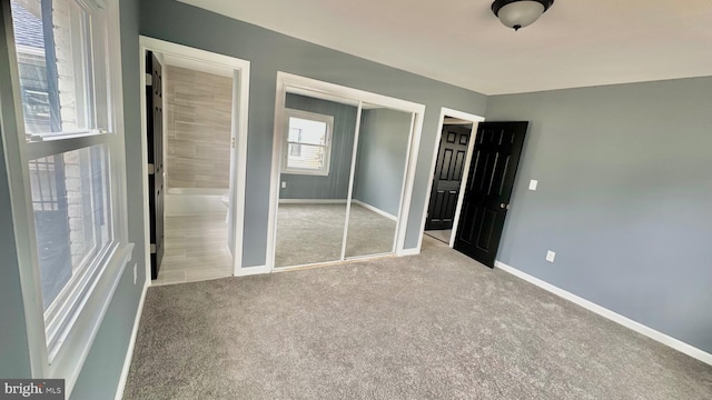 unfurnished bedroom with a closet, carpet flooring, and baseboards