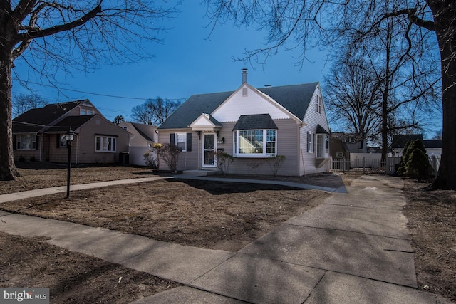 bungalow-style home with a shingled roof, central AC unit, and fence