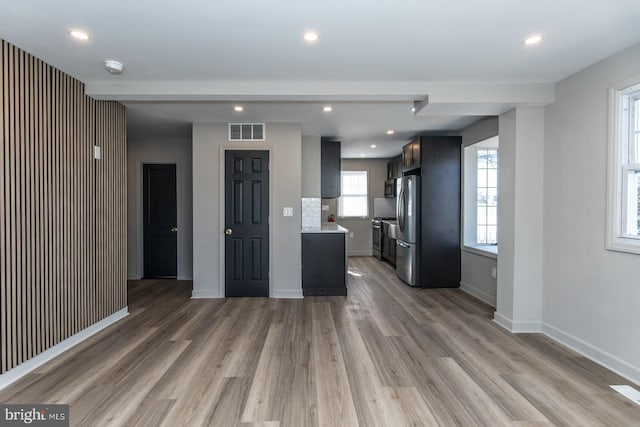 kitchen featuring light wood finished floors, stainless steel appliances, light countertops, visible vents, and baseboards