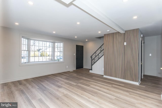 unfurnished living room featuring light wood-style flooring, stairs, beamed ceiling, and recessed lighting