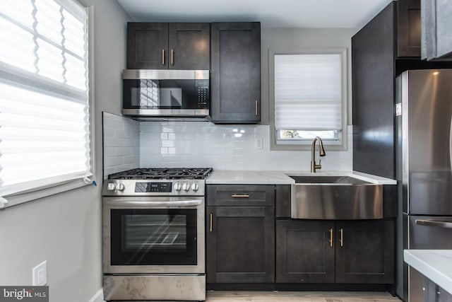 kitchen with a sink, appliances with stainless steel finishes, light stone counters, and backsplash