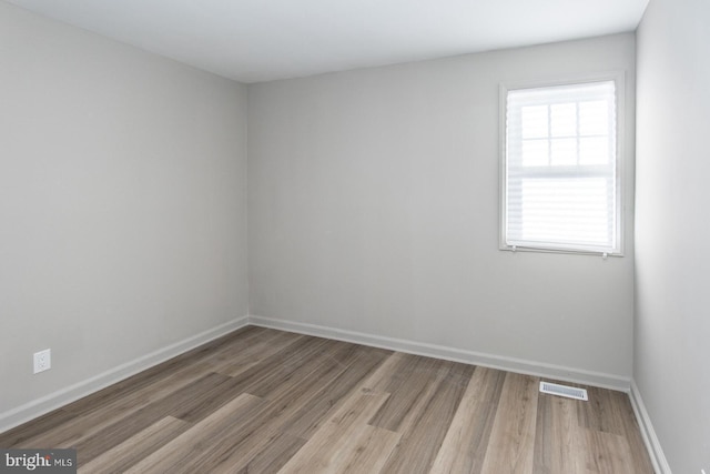 empty room featuring baseboards, visible vents, and light wood finished floors