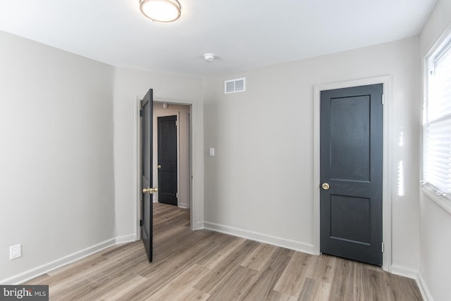 unfurnished room featuring a healthy amount of sunlight, light wood-type flooring, visible vents, and baseboards