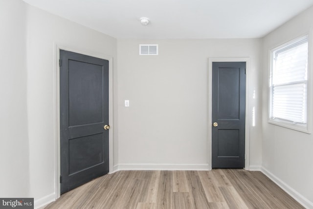 unfurnished room featuring visible vents, light wood-style flooring, and baseboards