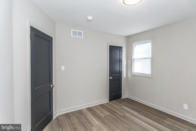 spare room with wood finished floors, visible vents, and baseboards