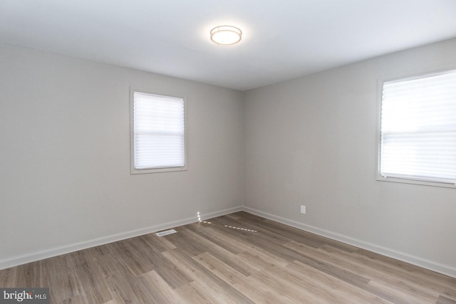 unfurnished room featuring baseboards, visible vents, and light wood-style floors