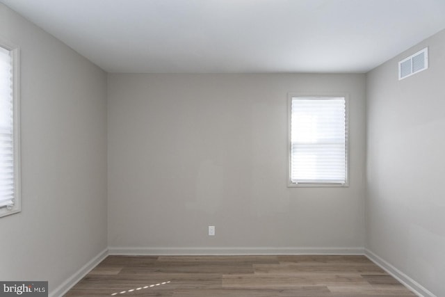 spare room featuring light wood-type flooring, visible vents, and baseboards