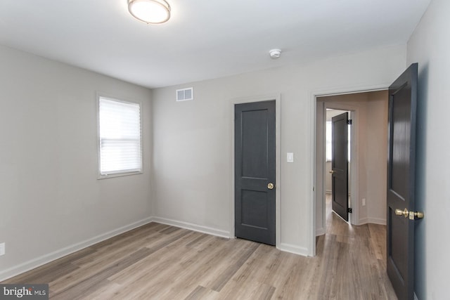 unfurnished bedroom featuring light wood-style floors, baseboards, and visible vents