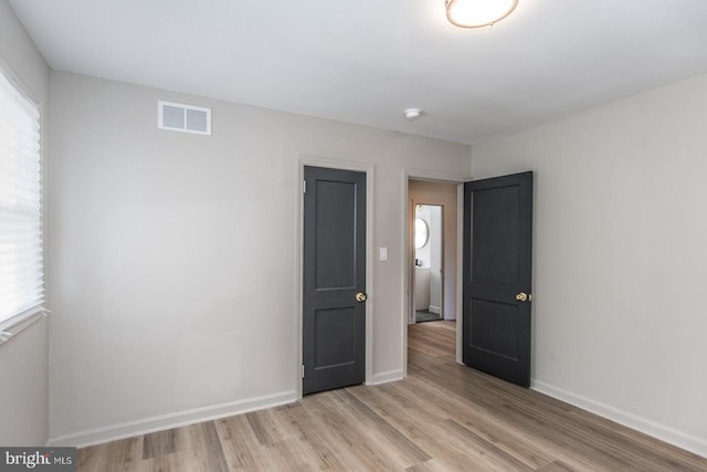 unfurnished bedroom with baseboards, visible vents, and light wood-style floors