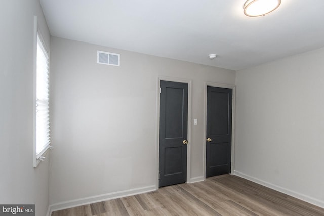 unfurnished bedroom with light wood-type flooring, visible vents, and baseboards