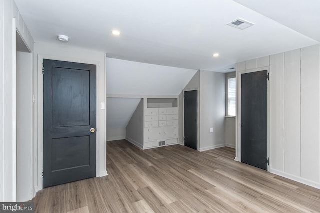 bonus room with lofted ceiling, light wood-style floors, baseboards, and visible vents