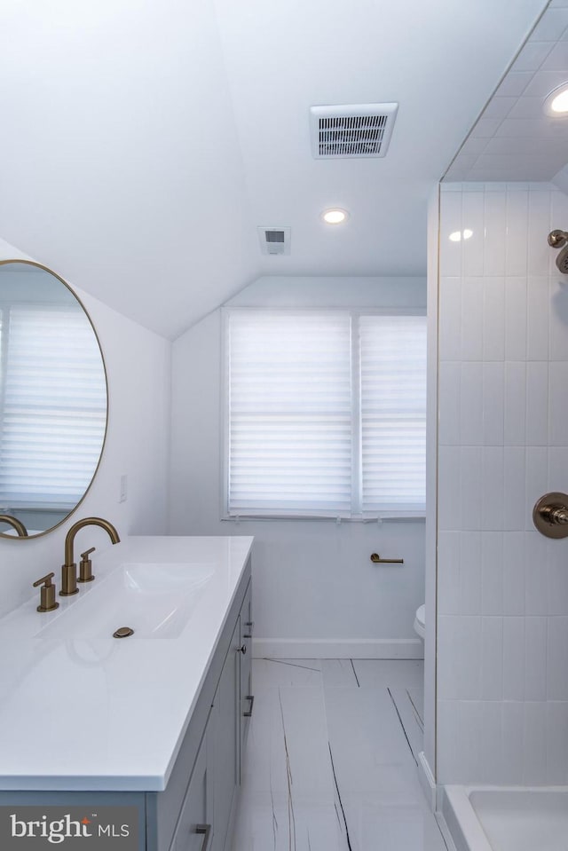 bathroom with vaulted ceiling, tiled shower, vanity, and visible vents