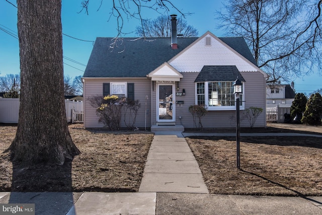 view of front of home with roof with shingles and fence