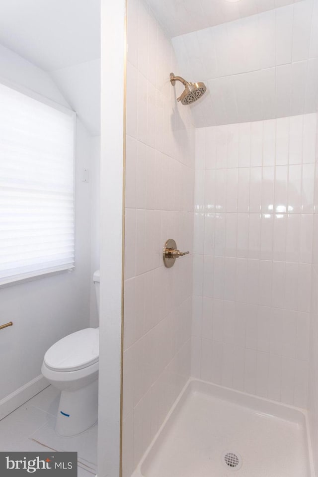 full bathroom featuring lofted ceiling, tiled shower, toilet, and baseboards