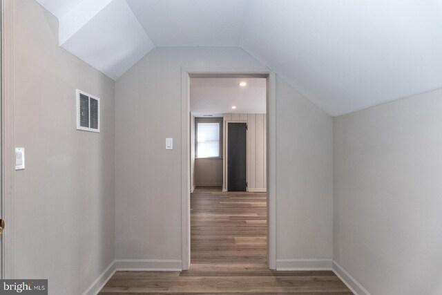 hallway featuring lofted ceiling, baseboards, visible vents, and wood finished floors